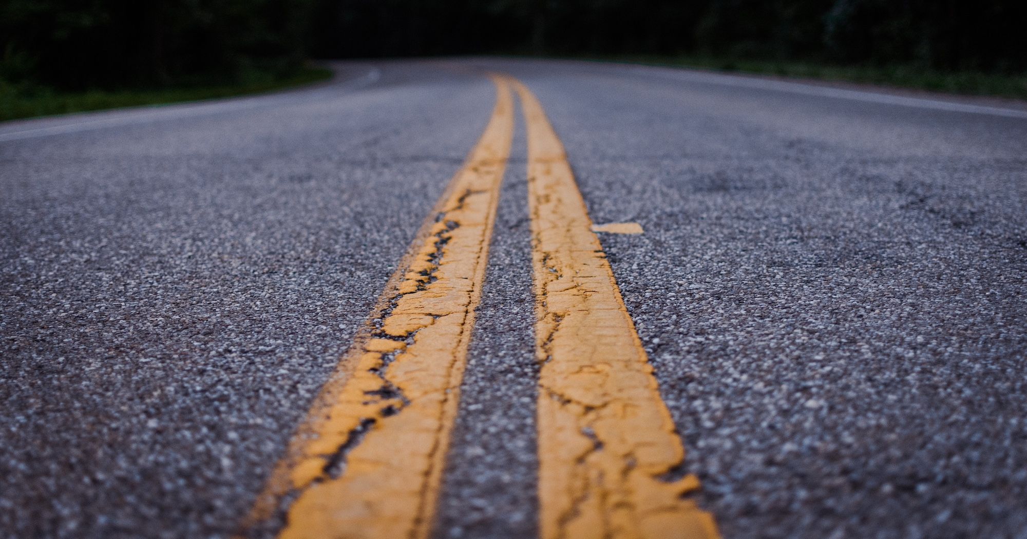 Close up of a gray concrete road with a yellow line.