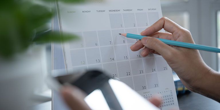 Pessoa anota no calendário com um lápis azul o número de dias que falta para terminar o período de carência do seguro