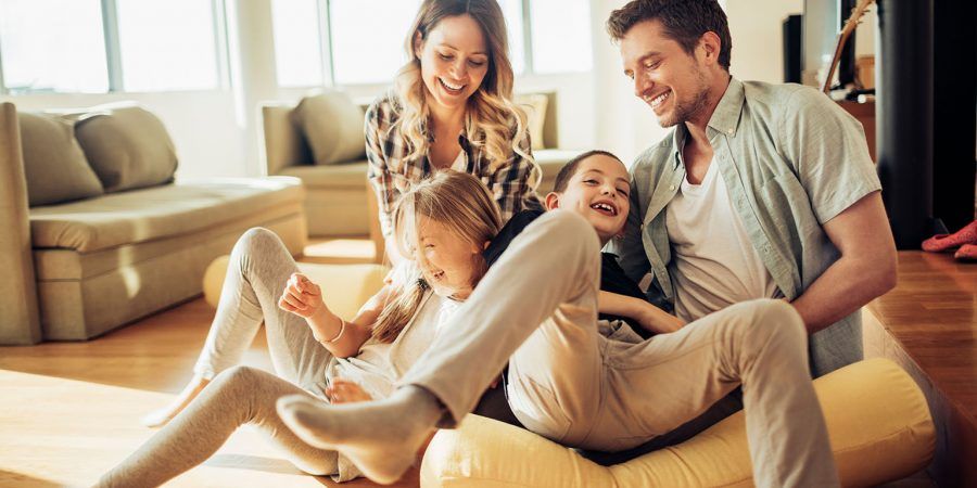 Pais e miúdos sentados no sofá com ar sorridente para ilustrar os aspetos a ter em conta no IRS para quem tem filhos