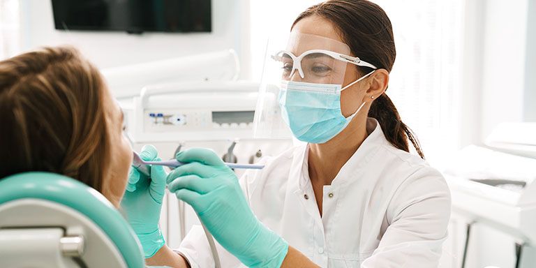 Dentista com óculos e máscara a cuidar dos dentes