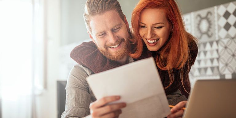 Casal, homem de barba e mulher ruiva. a sorrir porque descobriram a melhor solução para pagar dívidas