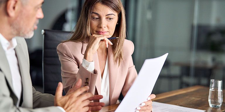 Mulher de casaco de fato cor de rosa suave analisa vários tipos de crédito