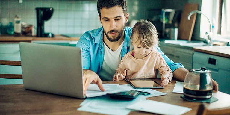 Pai com filha no colo ao computador analisa consequências de não pagar empréstimo