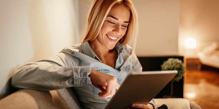 Mulher a sorrir enquanto trabalha no computador e descobre como rentabilizar as poupanças