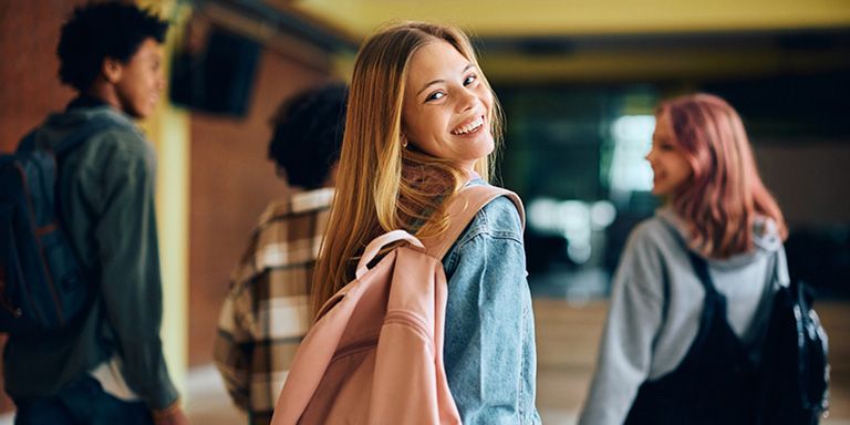 Rapariga de mochila às costas no regresso às aulas a sorrir