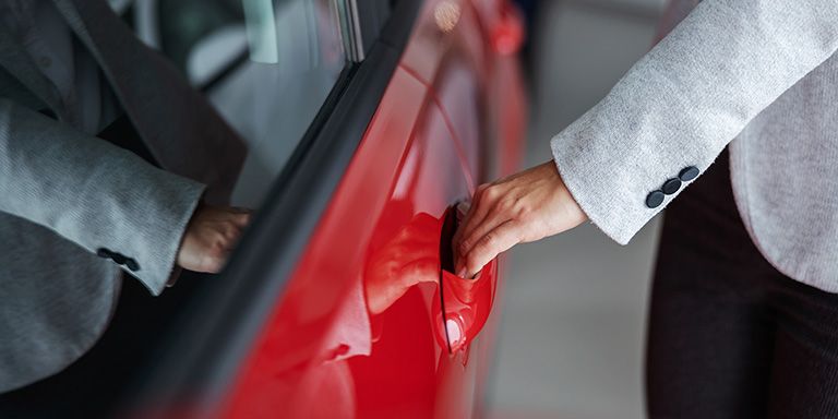 Mulher a abrir porta de carro vermelho: Leasing ou renting?